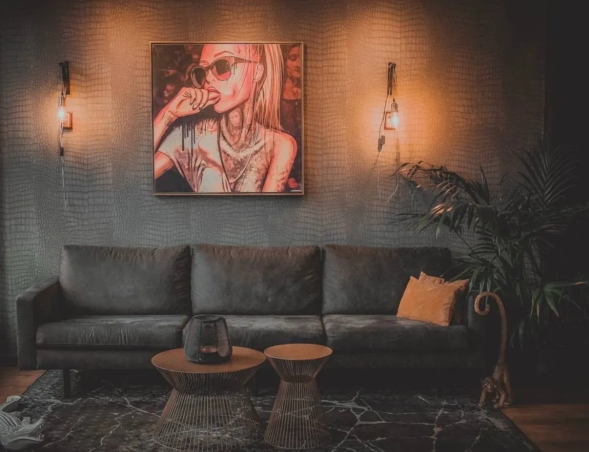 Lounge van de studio met warm wandlicht, leren bank en kunstwerk